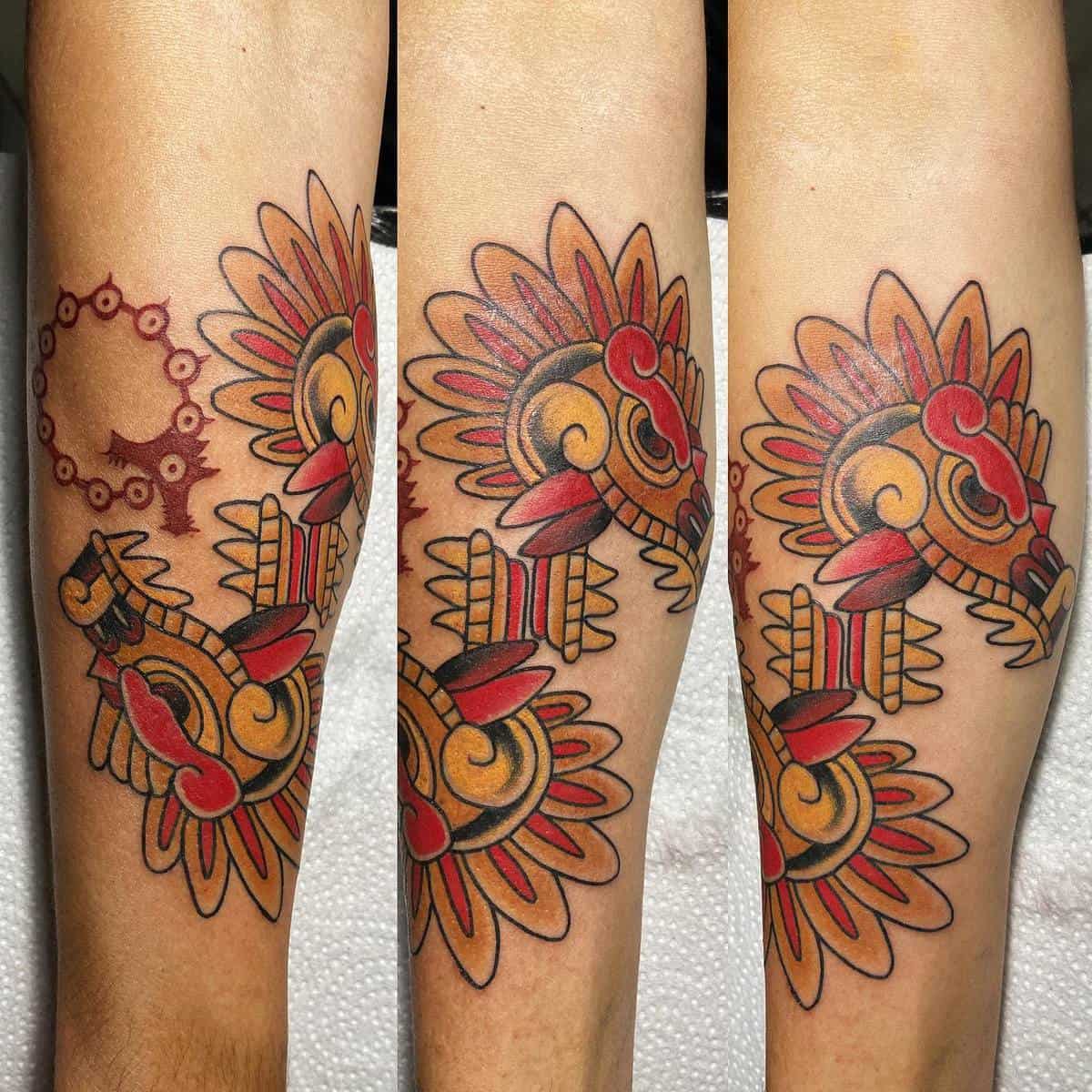 Colorful forearm tattoo of Quetzalcoatl in traditional Aztec style with bold red and yellow accents
