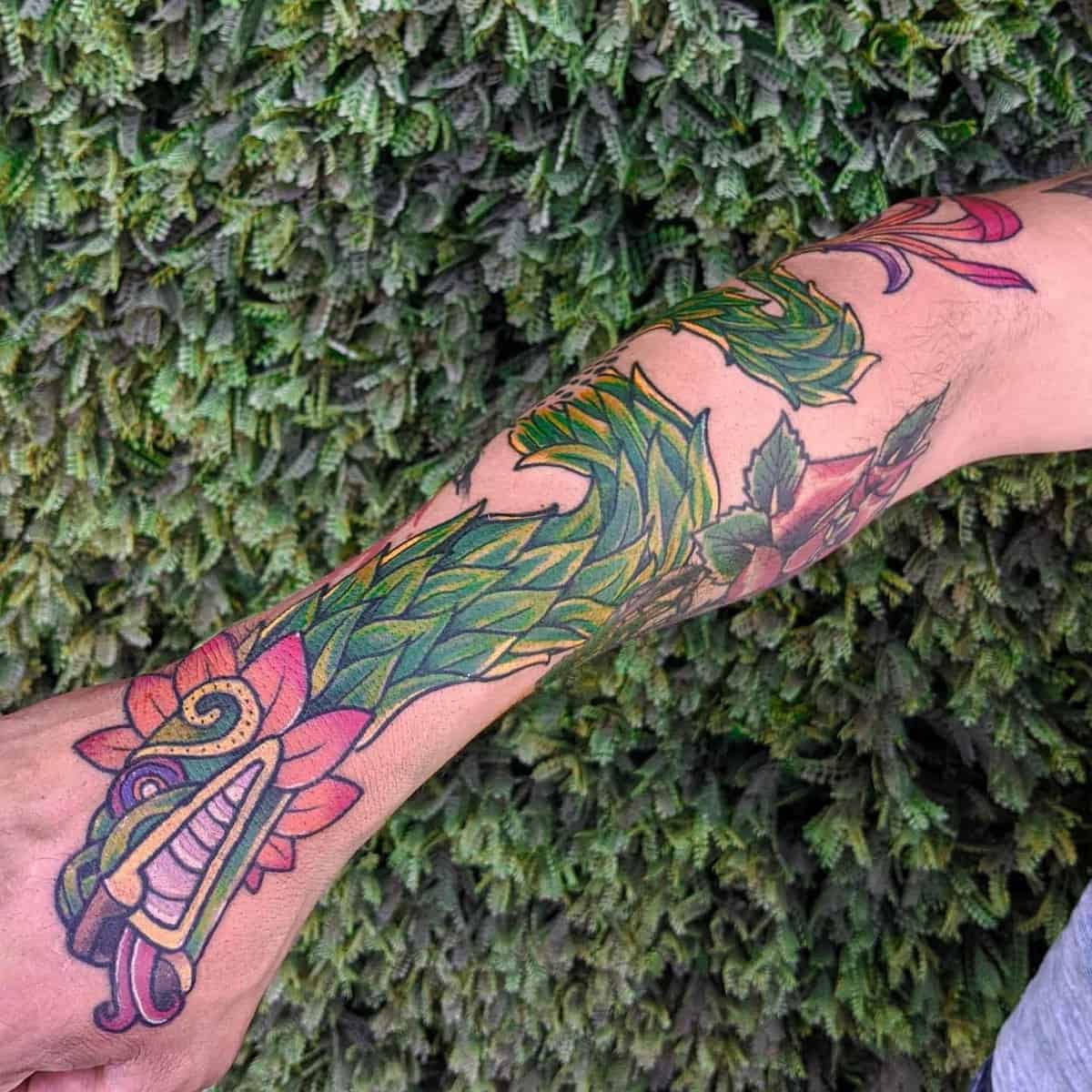 Vibrant forearm tattoo of Quetzalcoatl, featuring a colorful feathered serpent design