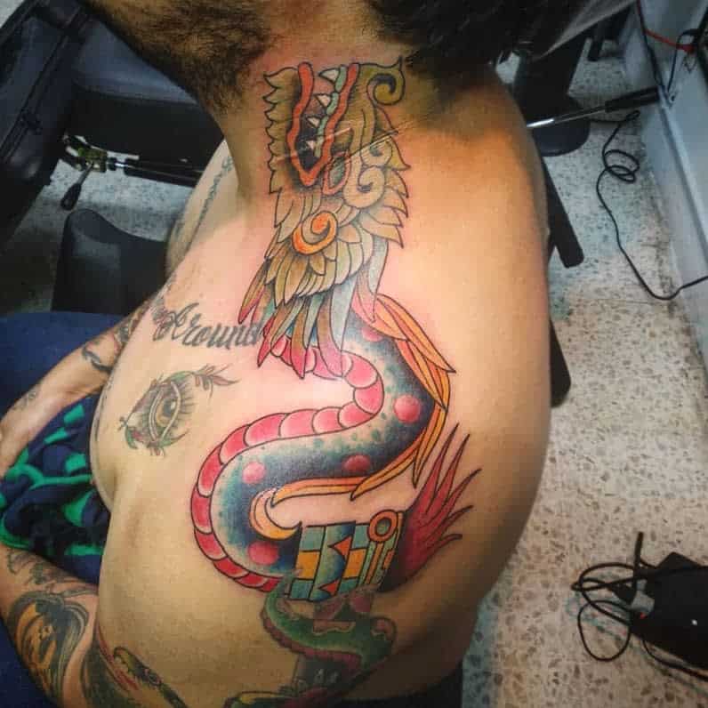 Vibrant shoulder and neck tattoo of Quetzalcoatl featuring bold colors and detailed feathers