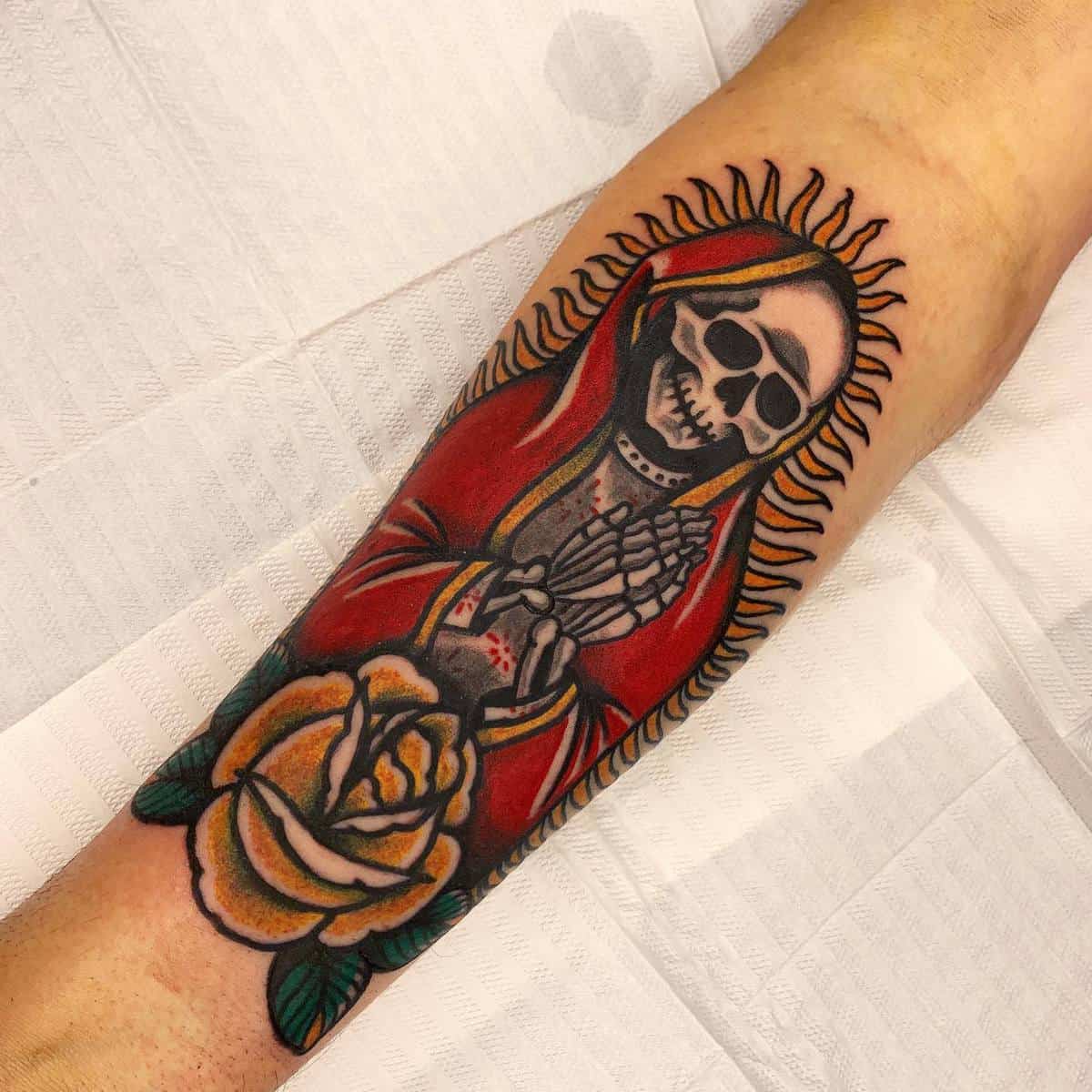 Bold Santa Muerte tattoo on the forearm with vibrant red and yellow colors, featuring a large rose