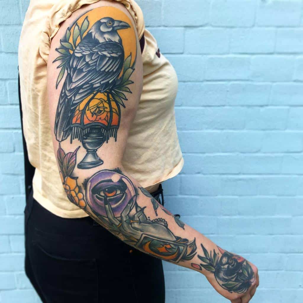 Woman with vibrant crow and lantern tattoo sleeve on left arm