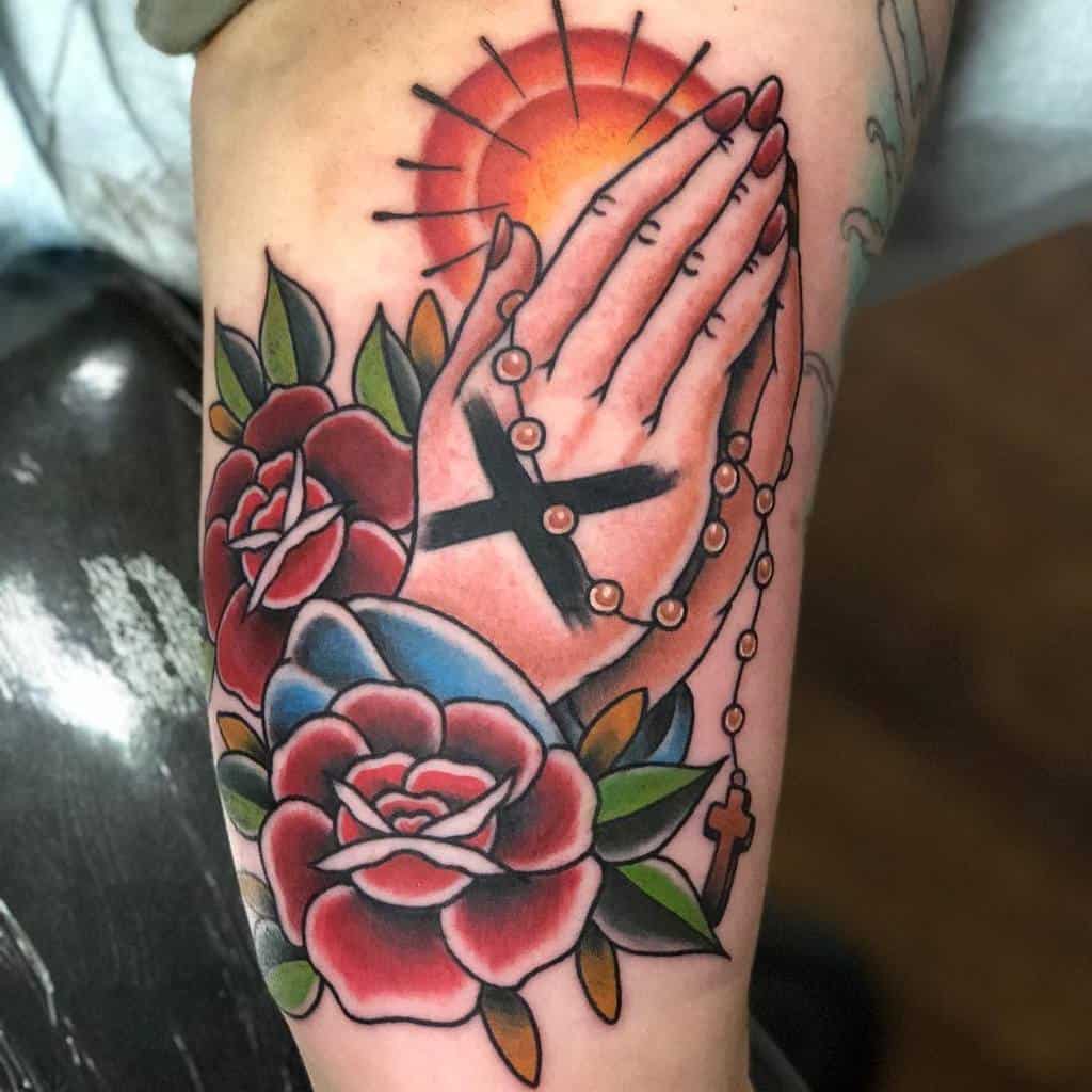 Straight edge tattoo of praying hands with a rosary, red roses, and a sunburst background
