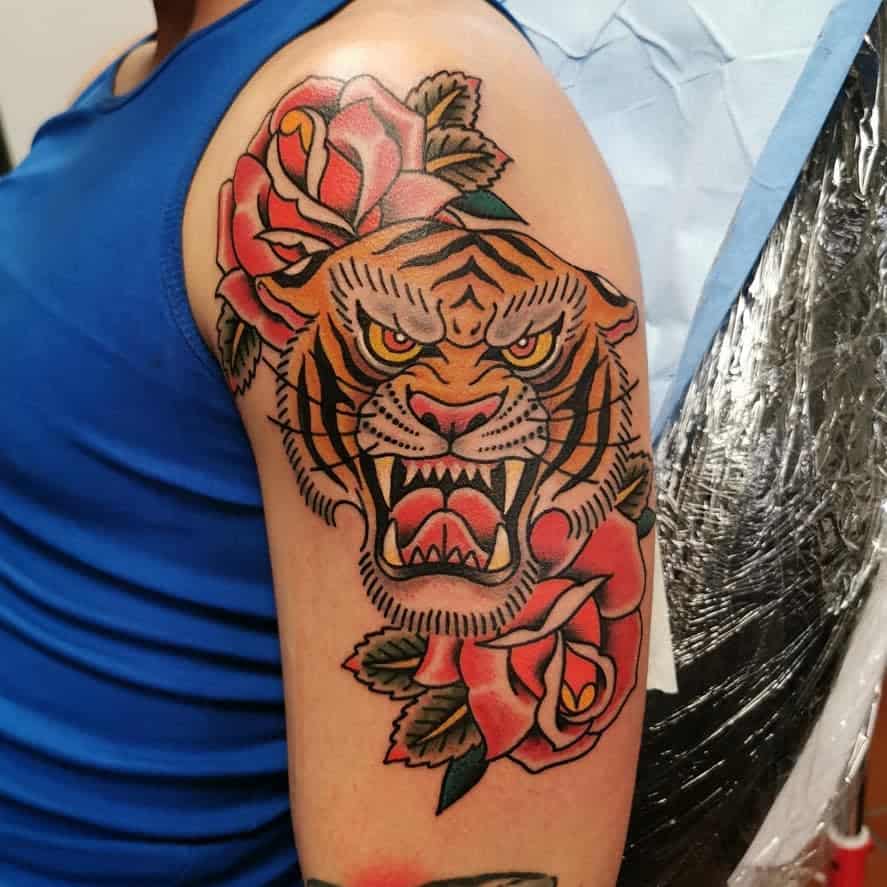 A tattoo of a snarling tiger with roses on a man's upper arm