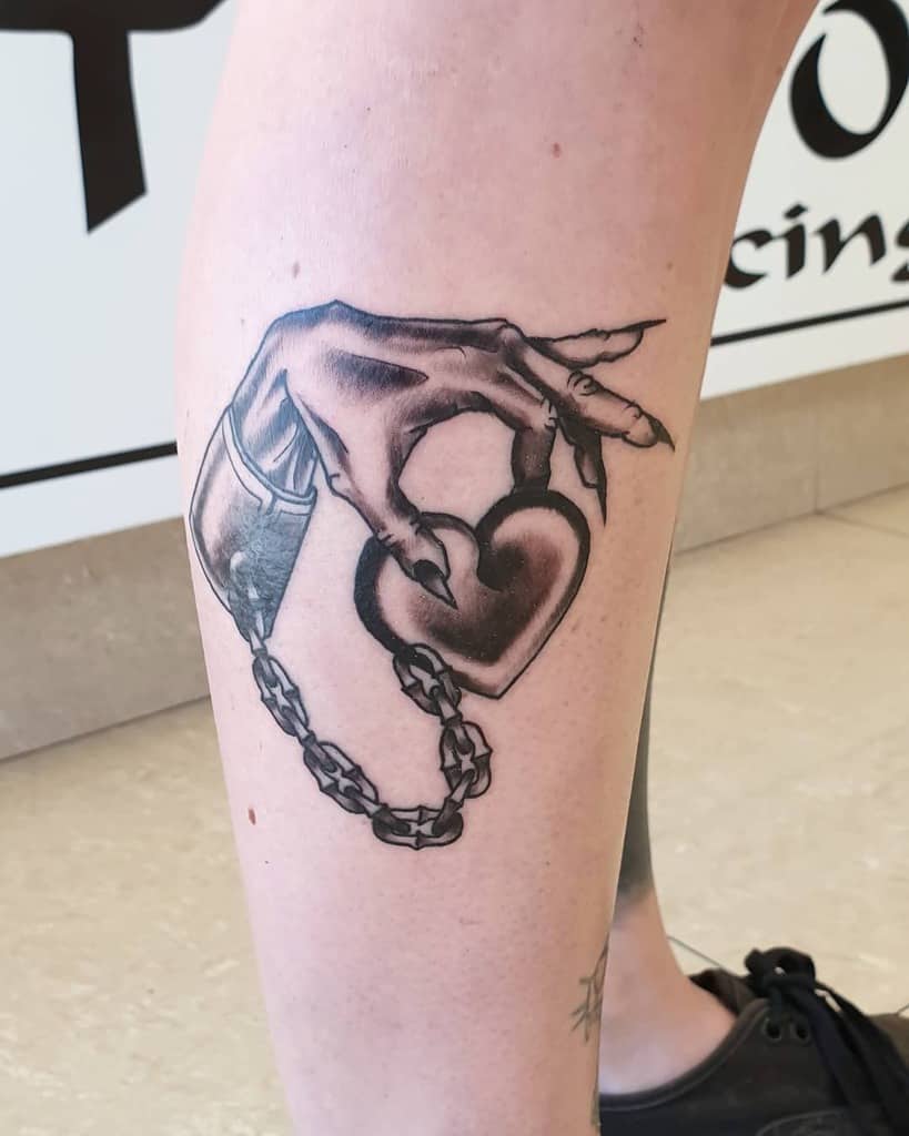 Tattoo of a hand holding a heart with a chain, in a realistic style