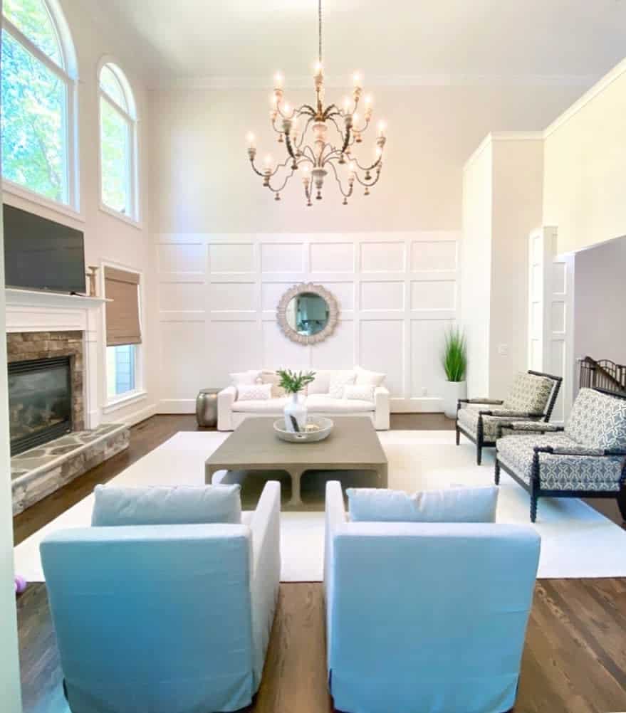 transitional white living room with blue accent chairs and candle chandelier