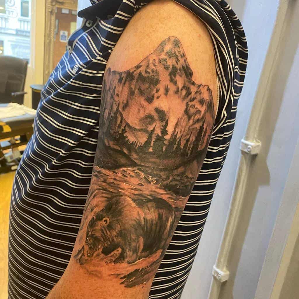 A detailed mountain and bear tattoo on an upper arm