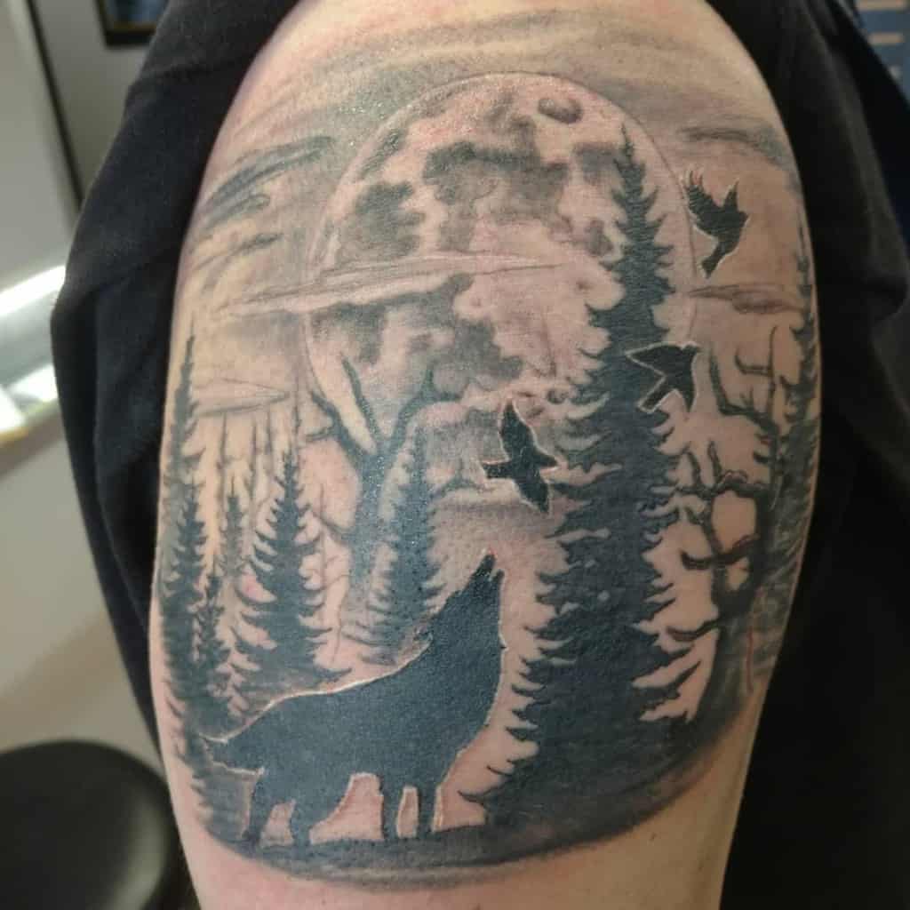 Tattoo of a wolf howling at the moon, surrounded by trees and flying birds
