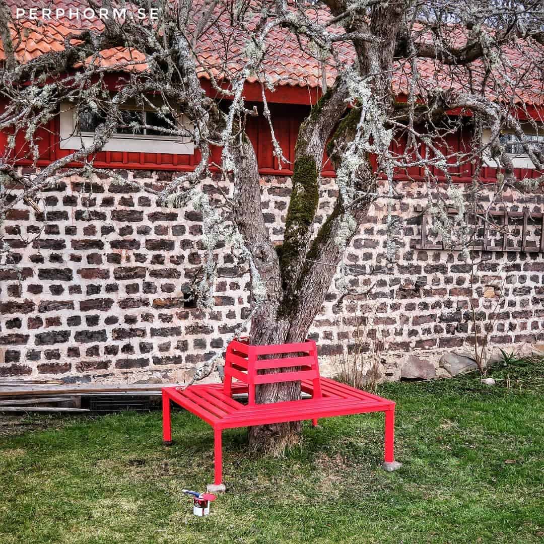 red square garden bench around old tree brick wall