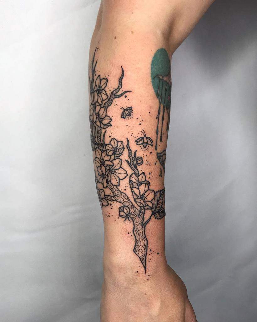 Arm tattoo depicting a blossoming branch with delicate butterflies