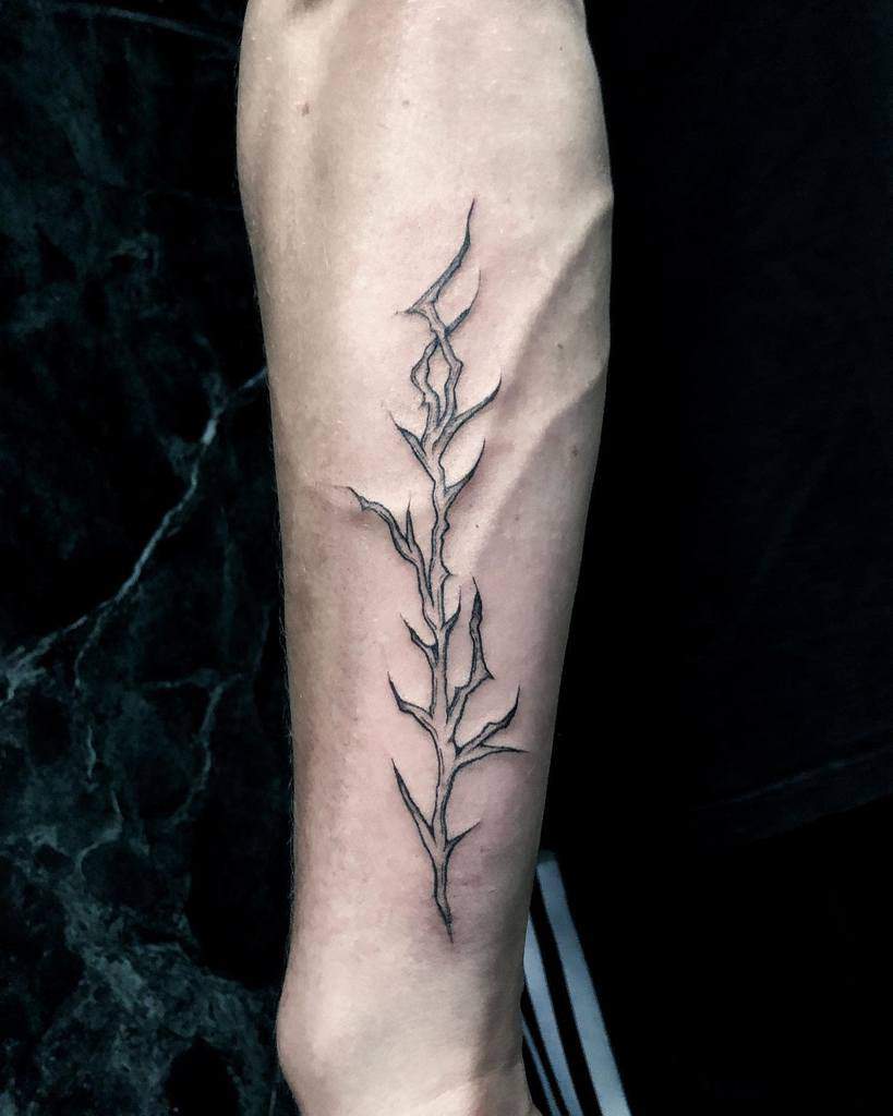 Minimalist tattoo of a delicate branch on a person's forearm