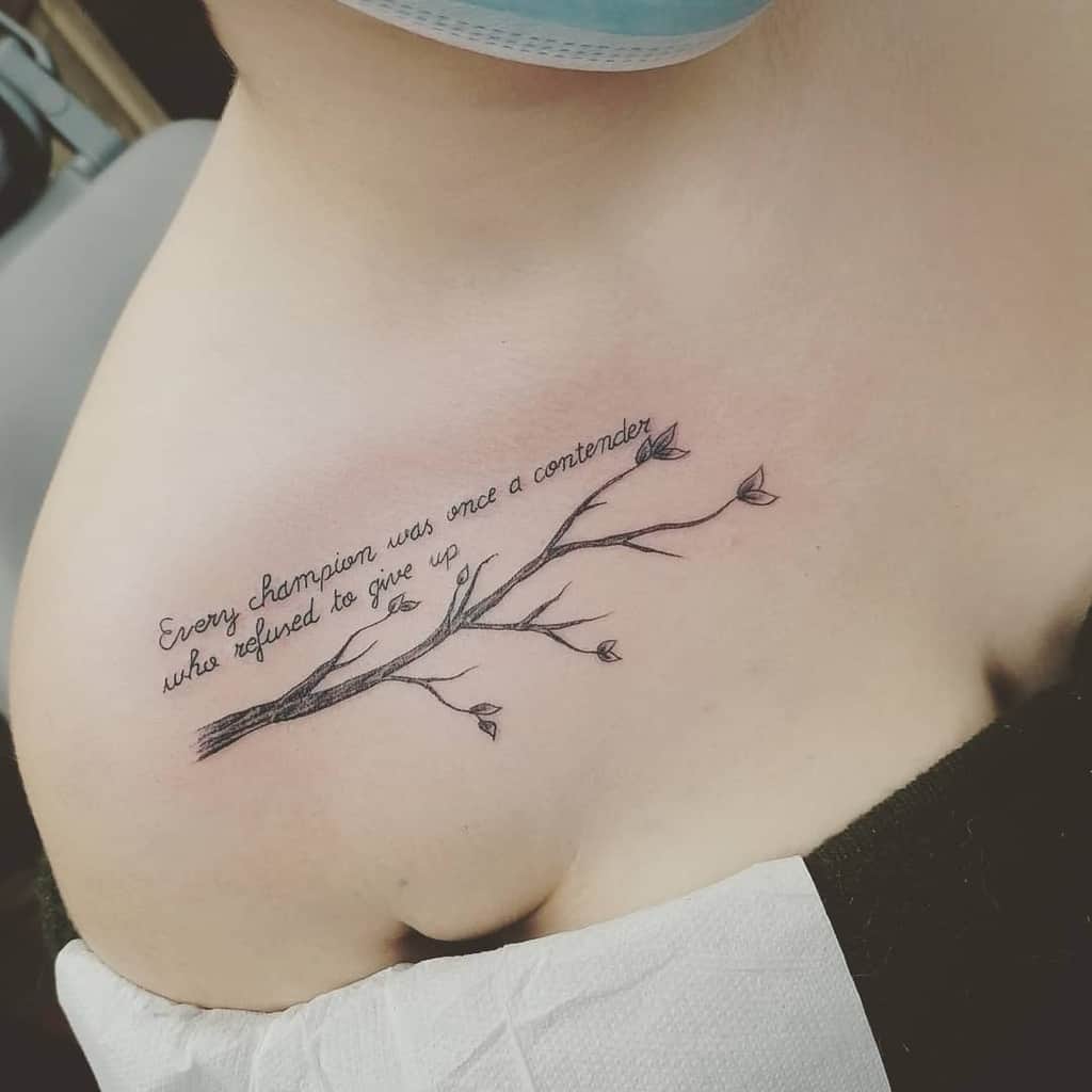 Tattoo of a branch with leaves on a person's chest, with text reading "Every champion was once a contender who refused to give up"