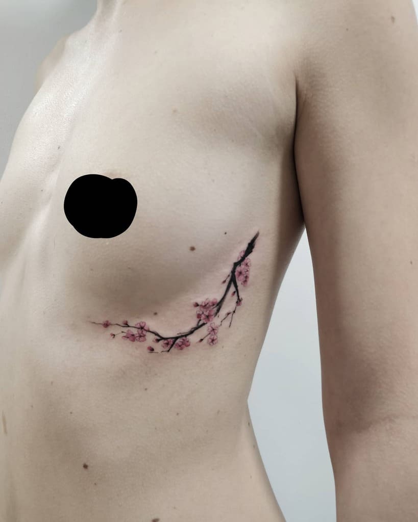 A person with a delicate cherry blossom branch tattoo gracefully inked on their ribcage