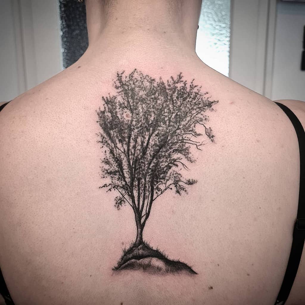Black and grey back tattoo of a finely detailed tree with delicate branches and shading, symbolizing growth, resilience, and a deep connection to nature.