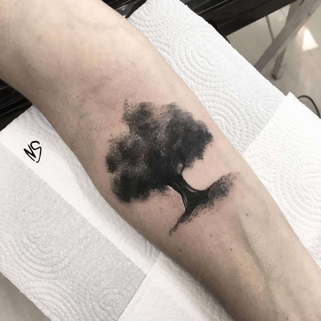 Forearm with a tree silhouette tattoo on textured white background