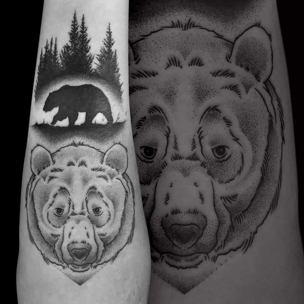Black and grey tattoo of a detailed bear face with a forest scene above, featuring a bear silhouette walking among pine trees, symbolizing strength and nature.