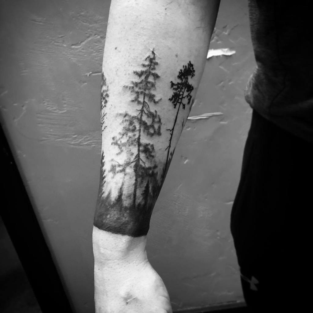 Black and white tattoo of trees on a wrist