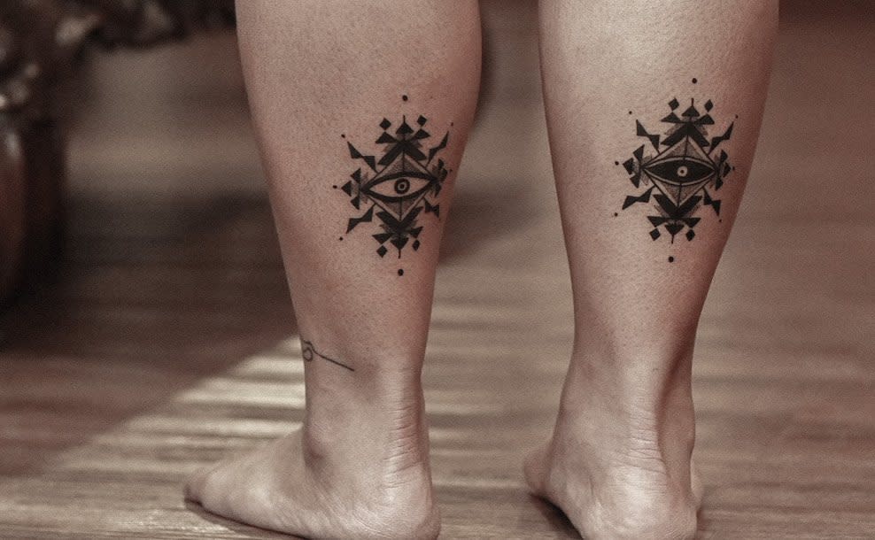 Calves with symmetrical geometric eye tattoos