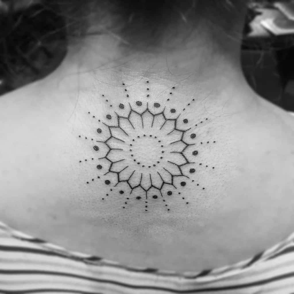 Black mandala dotwork tattoo on back, radiating from center