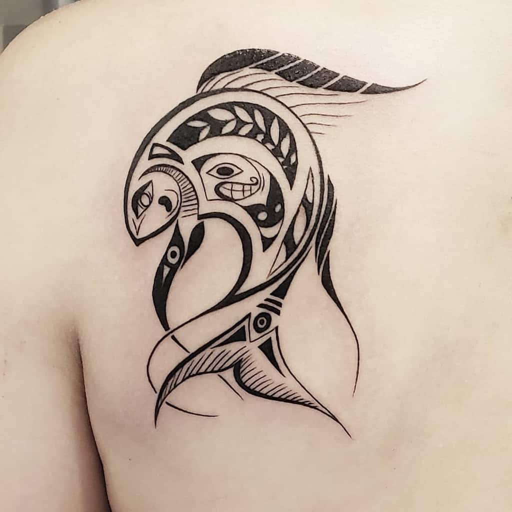 A tribal-style tattoo of a stylized fish design on a shoulder