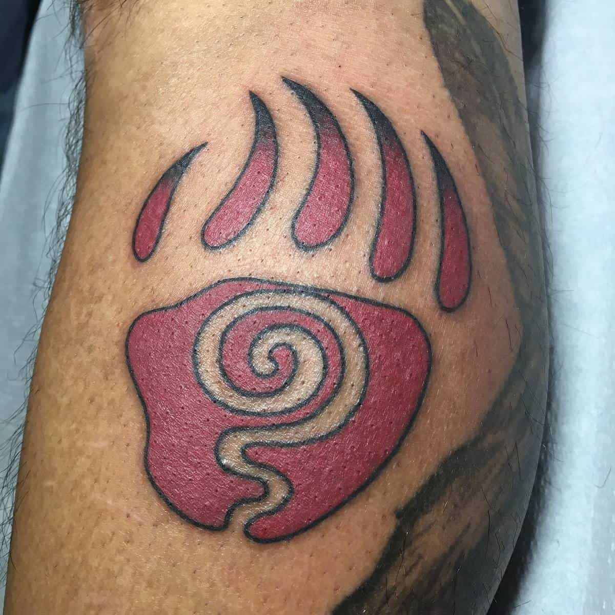 Tattoo of a stylized red bear paw with a black spiral design in the center
