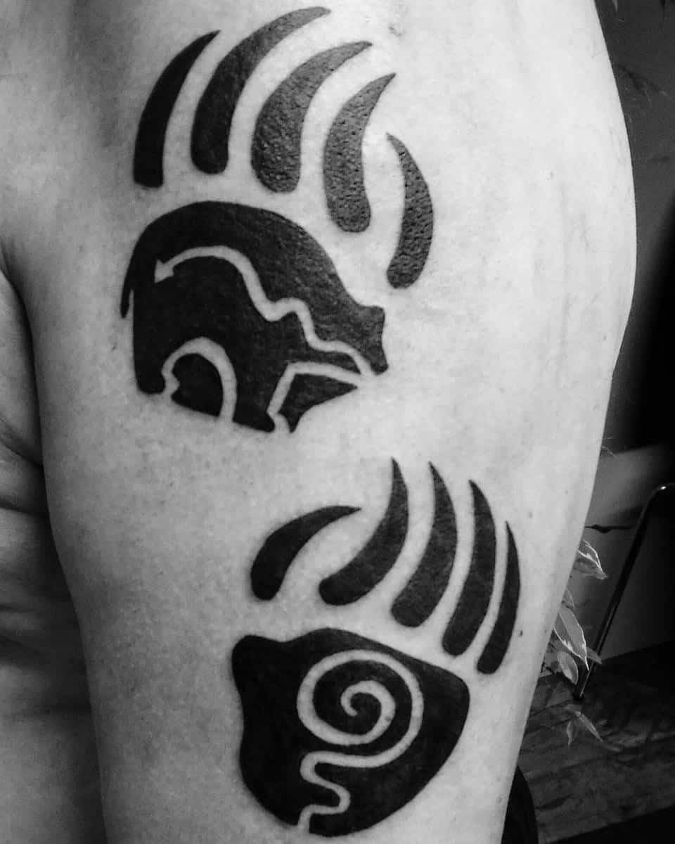 Black bear tattoo with claws and abstract design on upper arm