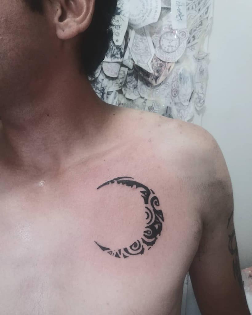A tribal crescent moon tattoo on a person's chest