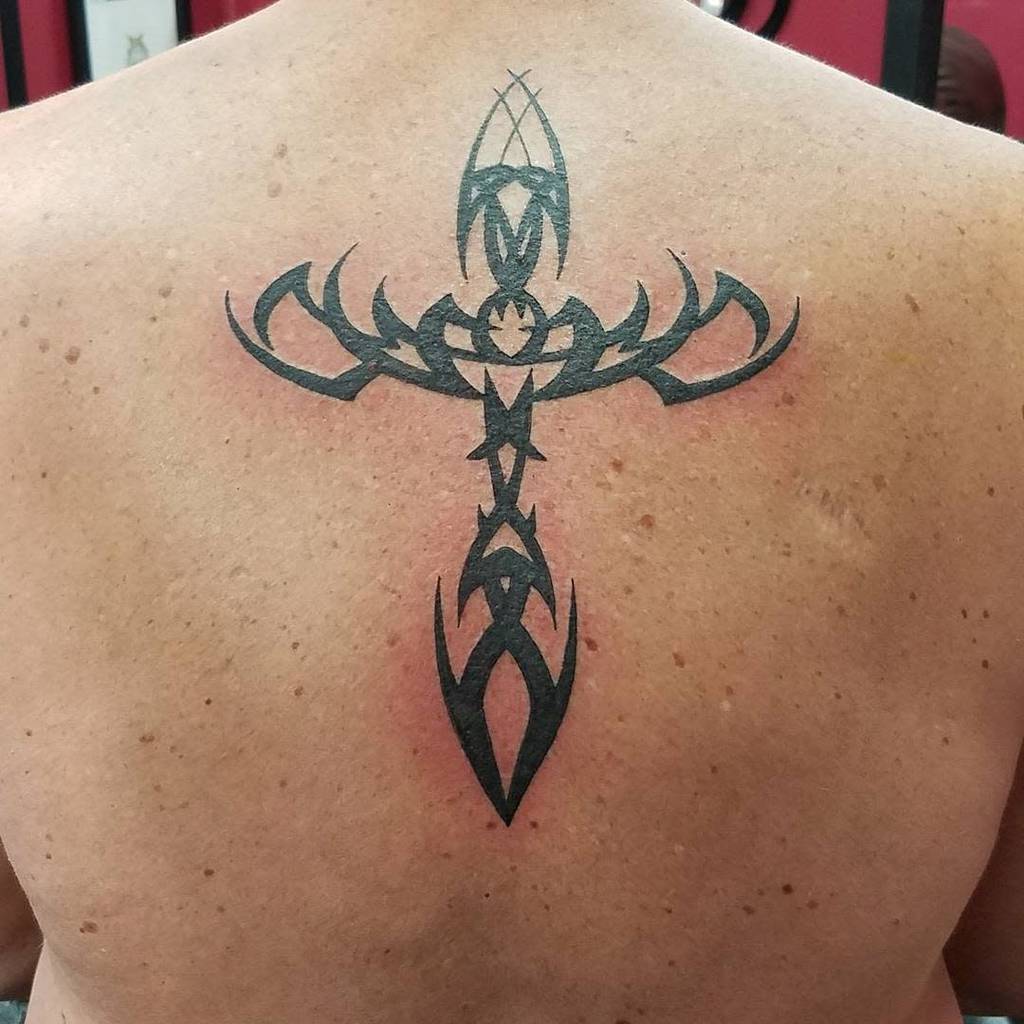 A back tattoo featuring a symmetrical tribal cross design