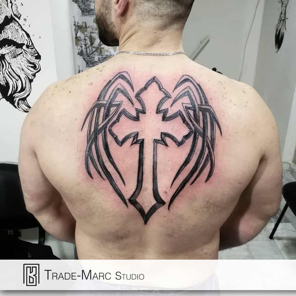 A man with a striking tattoo of a cross adorned with wings spans his back