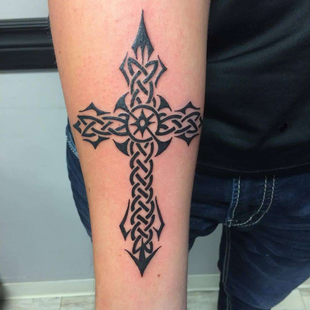 A stunning arm tattoo featuring a black Celtic cross, beautifully detailed with intricate knot patterns and elegantly pointed ends