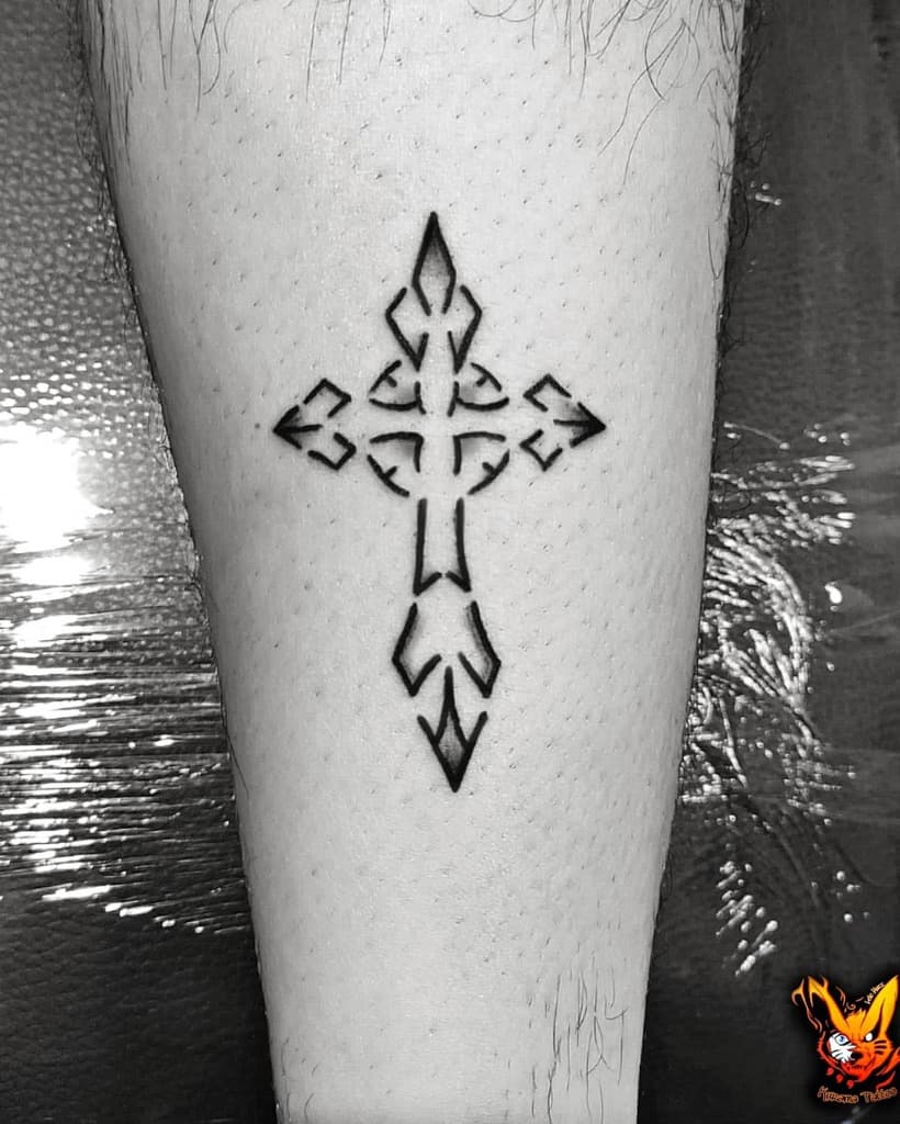 A black geometric cross tattoo graces a person's calf, boasting sharp angles and a stunning symmetrical design