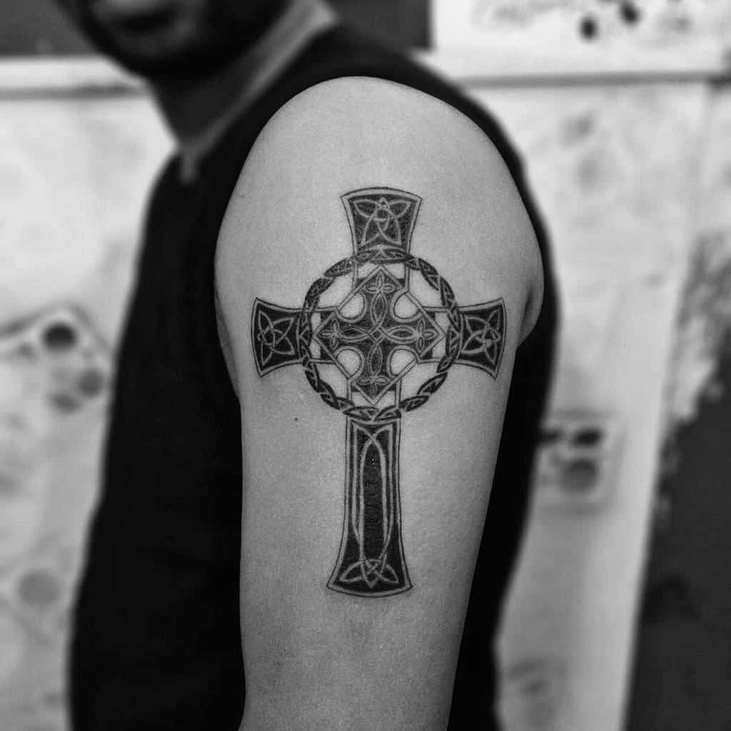 Celtic cross tattoo on a man's upper arm, with intricate knotwork and circle details