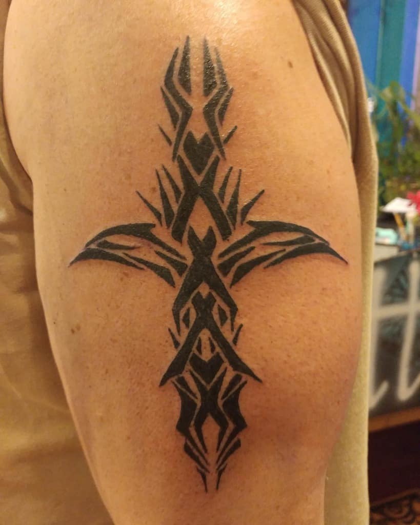 Abstract tribal-style tattoo featuring black geometric shapes on a person's upper arm