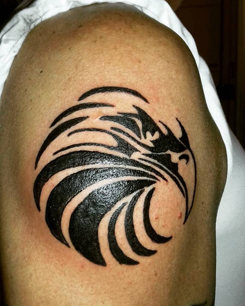 Tattoo of a stylized black eagle with tribal design on an upper arm