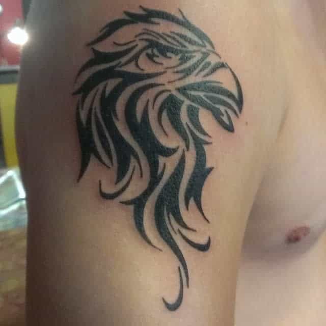 Tattoo of an eagle's head in tribal style on an upper arm