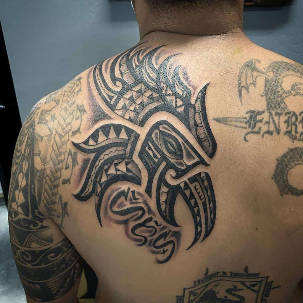 A detailed tribal-style tattoo of an eagle and geometric patterns covering their upper back and shoulder