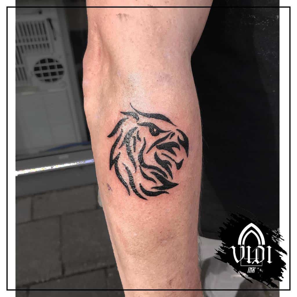 A tattoo of a stylized eagle's head in black ink on an inner forearm