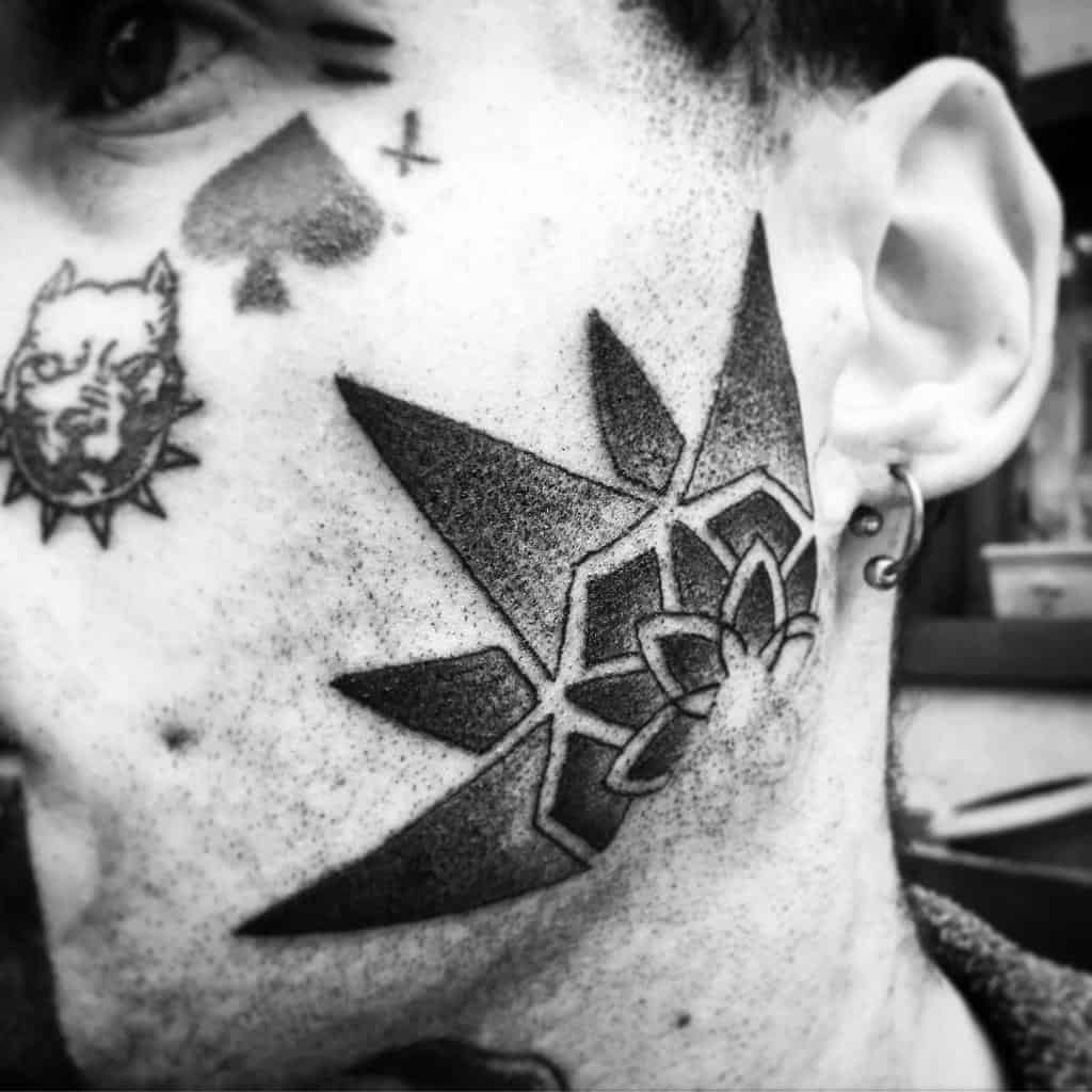Bold geometric and floral-inspired tribal tattoo covering the cheek, featuring sharp lines and intricate details