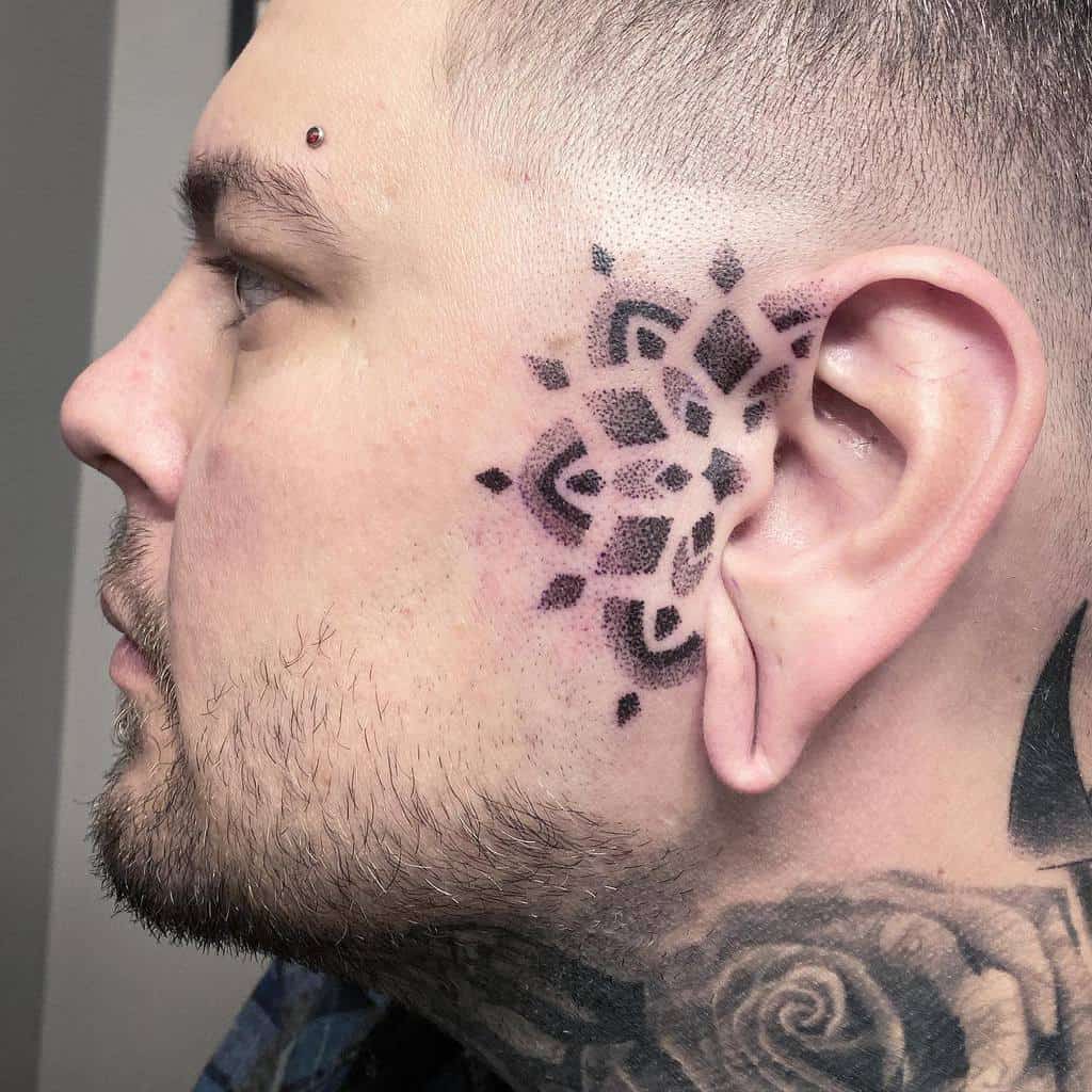 Side view of a person with a geometric floral-patterned tribal tattoo on the side of the face, extending from the ear
