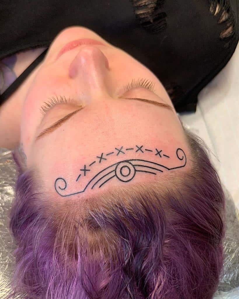 Minimalist tribal tattoo on the forehead, featuring simple lines, X-shaped patterns, and swirling curves forming an arched design