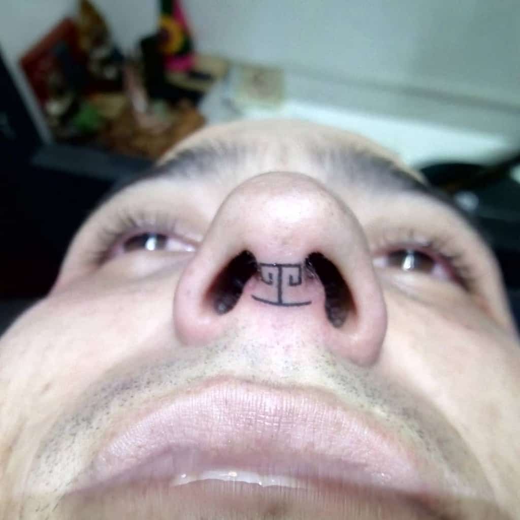 Man's nose tattoo featuring a geometric pattern under the nostrils with precise symmetrical lines