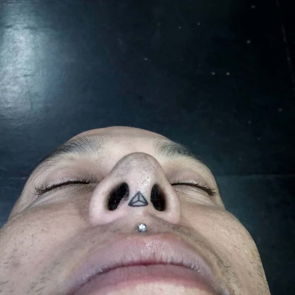 Triangle tattoo on the nose between nostrils