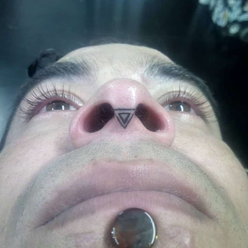 Man's nose tattoo featuring a triangle with a double line design between the nostrils