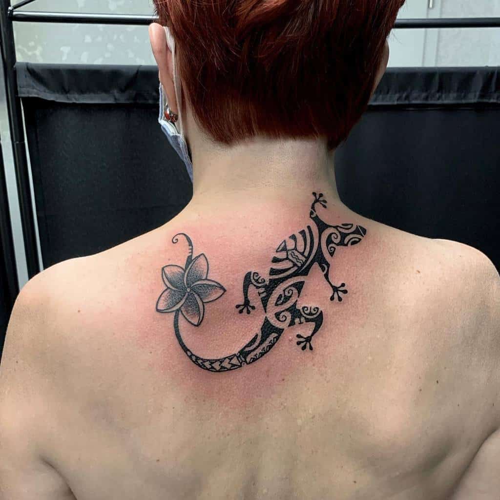 Back tattoo of a tribal lizard with geometric shapes and a simple flower, blending elegance and strength