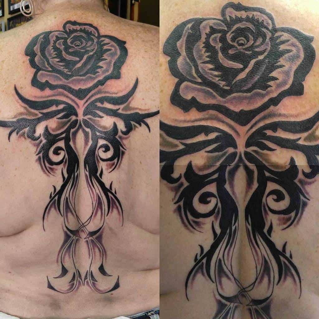 Back tattoo of a stylized black rose with intricate swirling designs extending down the spine