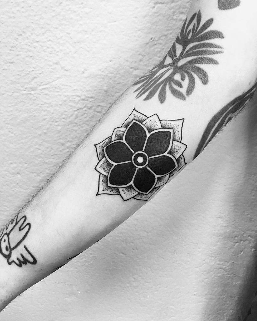 Black flower tattoo on forearm, with abstract designs around