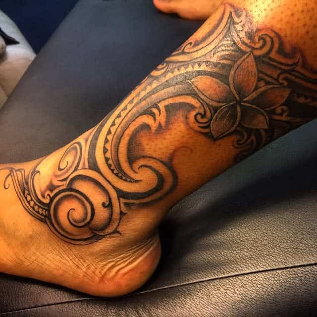 Bold tribal leg tattoo with swirling patterns and a central flower design, blending Samoan-style motifs and nature