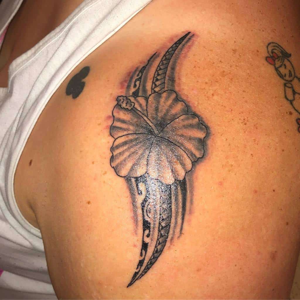 Bold shoulder tattoo featuring a hibiscus flower paired with Polynesian tribal patterns, creating a striking and elegant design