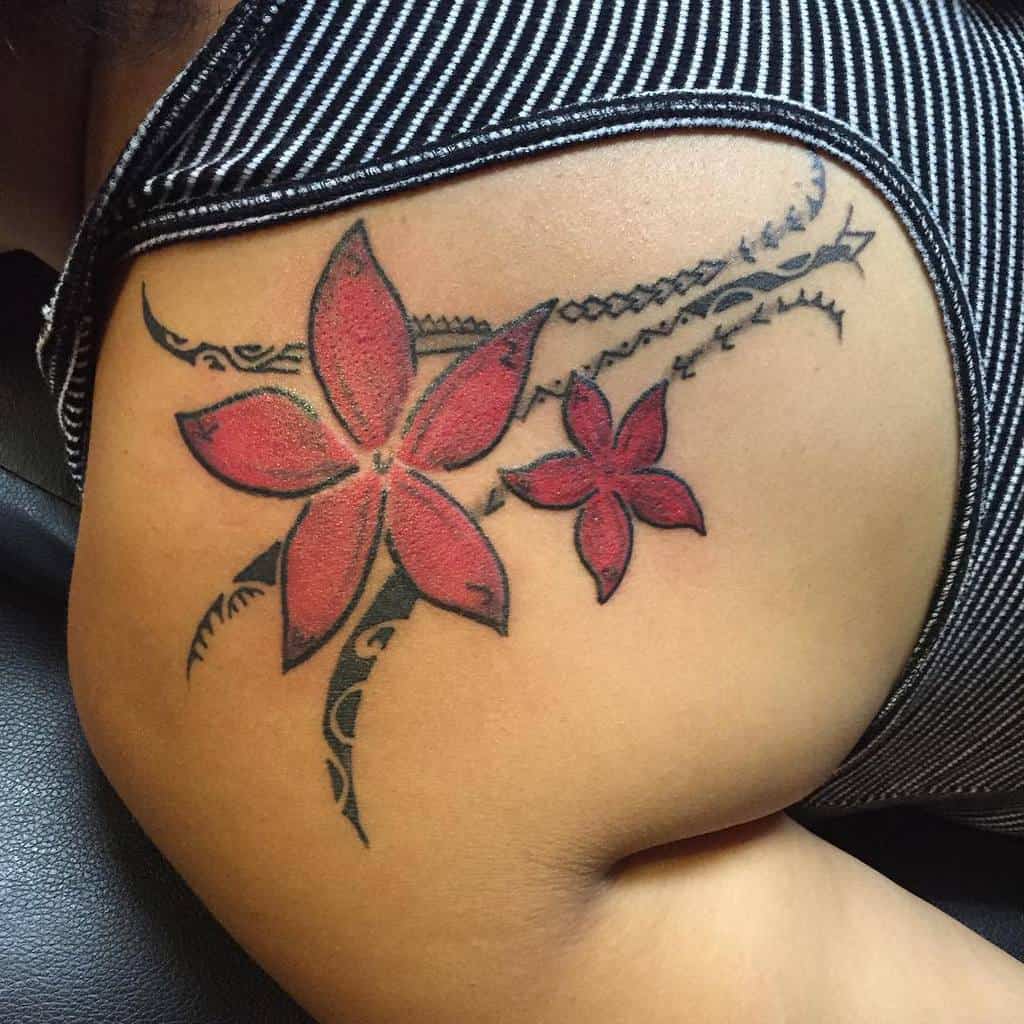 Vibrant shoulder tattoo featuring red flowers intertwined with Polynesian tribal elements, blending nature with traditional patterns