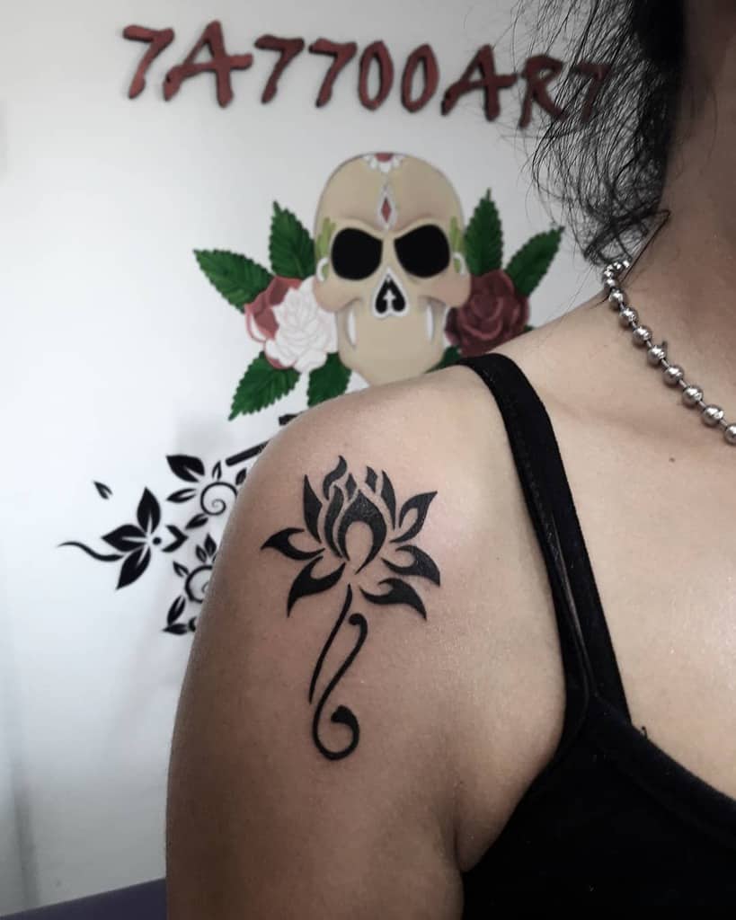 Tattoo of a stylized flower on a woman's shoulder