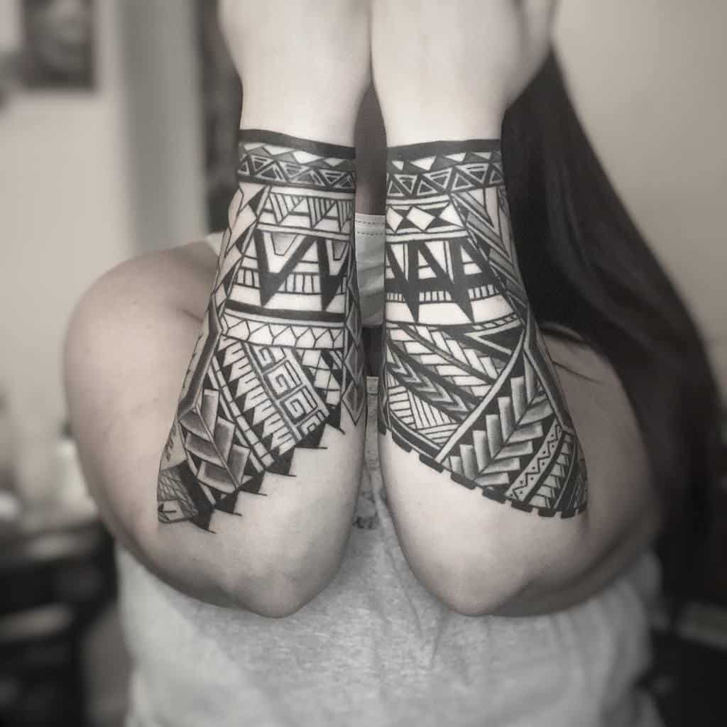 Forearms with intricate geometric tribal tattoos, arms crossed, monochrome